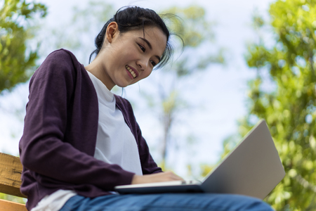 Beautiful young woman using laptop at outdoorの写真素材