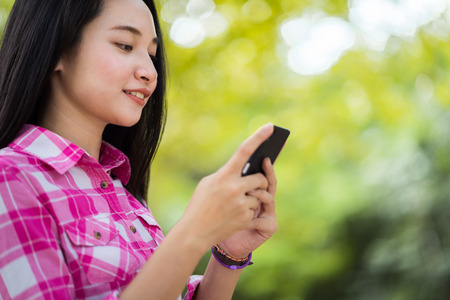 Asian student girl text messaging in the parkの写真素材
