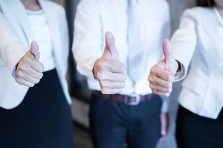 Three business partners keeping thumbs upの写真素材
