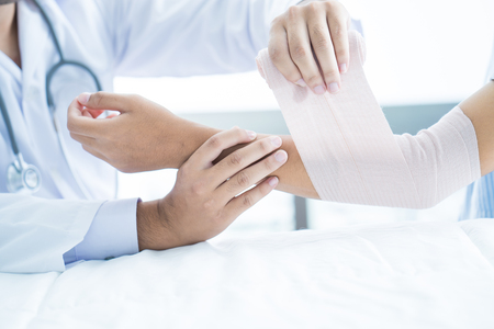 Close-up doctor is bandaging upper limb of patient.の写真素材