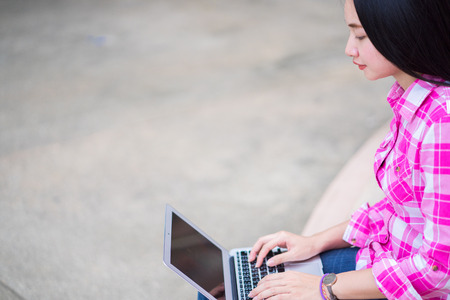 Beautiful young woman using laptop at outdoorの写真素材
