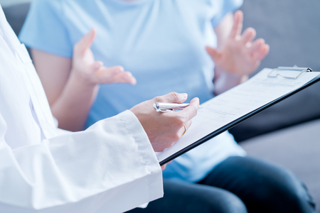 Woman doctor talking to her male patient at officeの写真素材