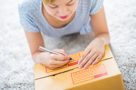 Woman signs papers among parcels. Delivery conceptの写真素材