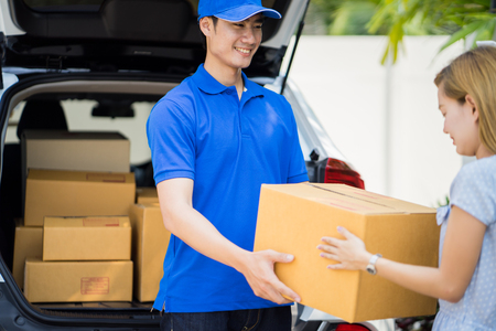 Asian woman receiving a package at home from a delivery guyの写真素材