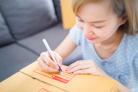 Woman signs papers among parcels. Delivery conceptの写真素材