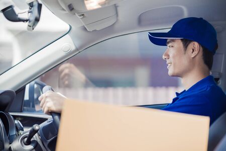 Delivery man driving his van with packages on the front seatの写真素材