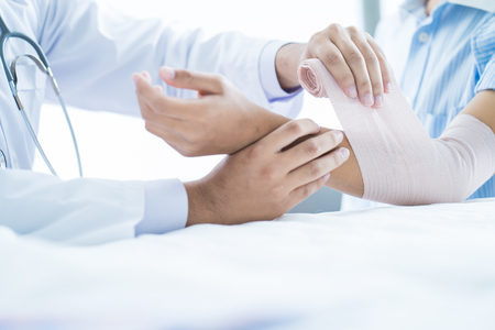 Close-up doctor is bandaging upper limb of patient.の写真素材