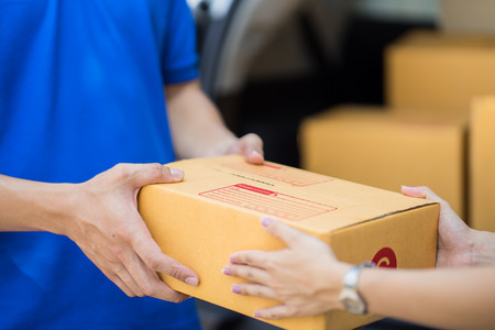 Asian woman receiving a package at home from a delivery guyの写真素材