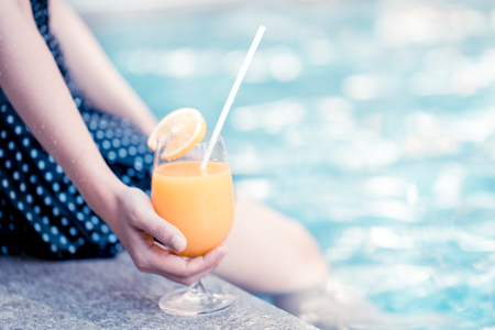 Young woman with cocktail in swimming pool