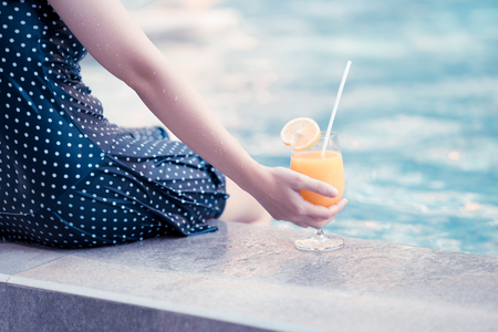 Young woman with cocktail in swimming poolの写真素材