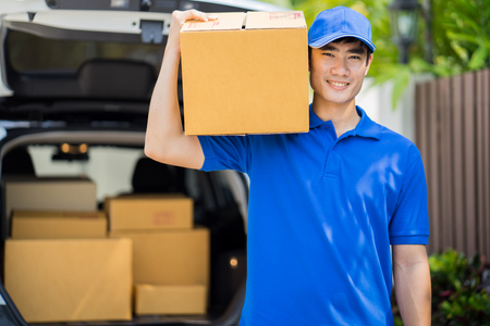 Delivery concept - postman in blue uniform holding packageの写真素材
