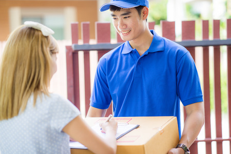 Asian woman receiving a package at home from a delivery guy