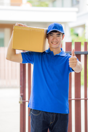 Delivery concept - postman in blue uniform holding packageの写真素材