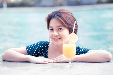 Young woman with cocktail in swimming poolの写真素材