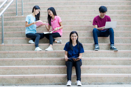 Group of happy teen high school asian students sitting on staircaseの写真素材