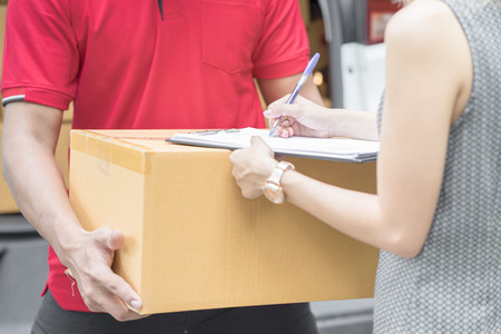 Asian woman receiving a package at home from a delivery guy