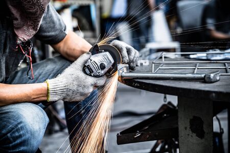 Asian worker making sparks while welding steel