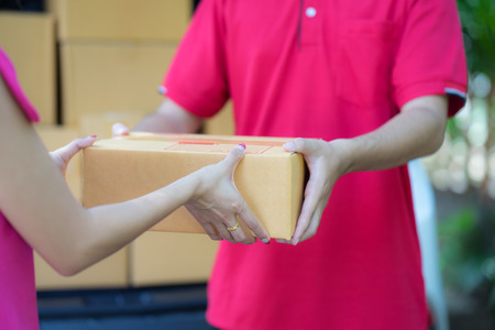 Asian woman receiving a package at home from a delivery guyの写真素材