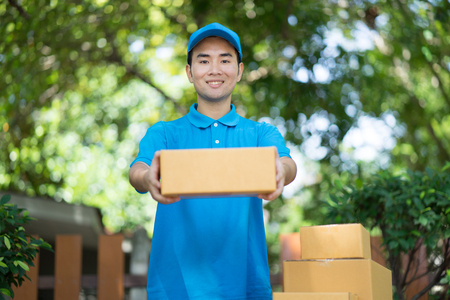 Asian Postman in blue uniform holding package. Delivery conceptの写真素材