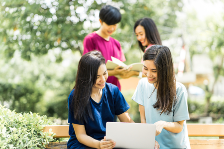 Group of Asian students sharing with the ideas on the campus lawnの写真素材