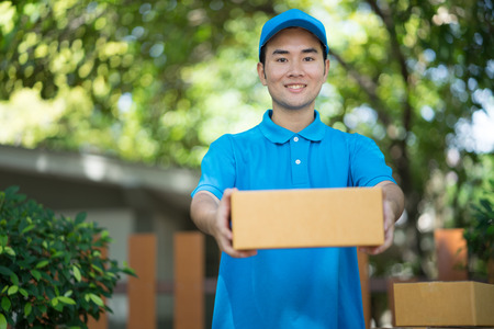 Asian Postman in blue uniform holding package. Delivery conceptの写真素材