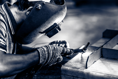 Asian worker making sparks while welding steelの写真素材