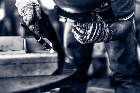 Asian worker making sparks while welding steel
