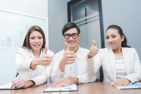 Three business partners keeping thumbs upの写真素材