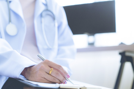 Close-up view of female doctor hands filling patient registration form. Healthcare and medical conceptの写真素材