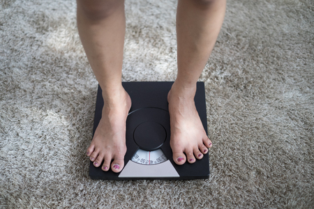 Slim woman on weighting scalesの写真素材