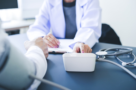 Close-up of patient arm during blood pressure measuring at medical consultation