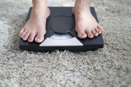 Slim woman on weighting scalesの写真素材