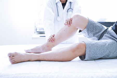 Close-up of male physiotherapist massaging the leg of patient in a physio room.の写真素材