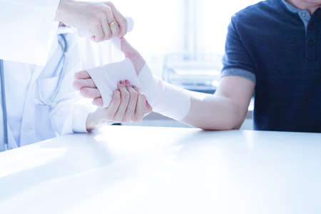 Close-up doctor is bandaging upper limb of patient.の写真素材