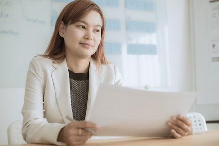 Asian business woman reviewing data in financial charts and graphs. Accountingの写真素材