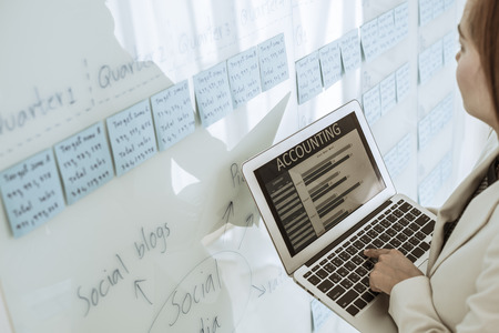 Asian business woman reviewing data in financial charts and graphs. Accounting