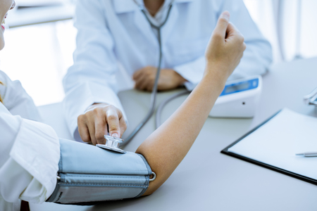 Doctor visiting a patient and checking her blood pressure at the hospitalの写真素材