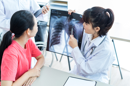 Woman Doctor Looking at X-Ray Radiography in patient's Roomの写真素材