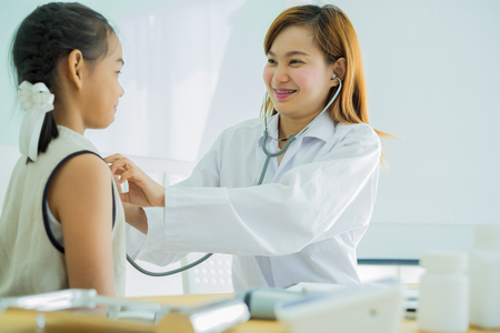 Asian doctor examining a little girl by stethoscopeの写真素材