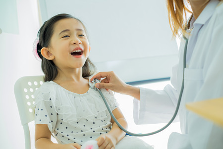 Asian doctor examining a little girl by stethoscopeの写真素材