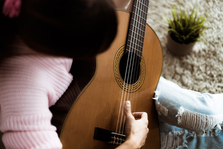 A beautiful asian woman playing acoustic guitar