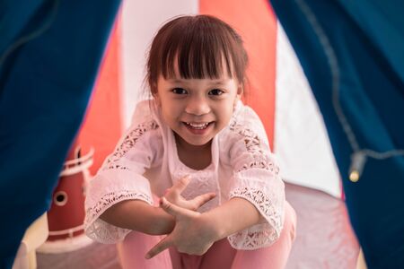 Asian children girl reading book in tent at nightの写真素材