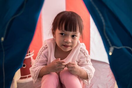 Asian children girl reading book in tent at nightの写真素材