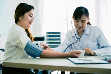 Doctor visiting a patient and checking her blood pressure at the hospitalの写真素材