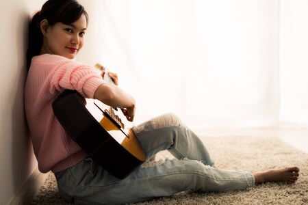 A beautiful asian woman playing acoustic guitarの写真素材