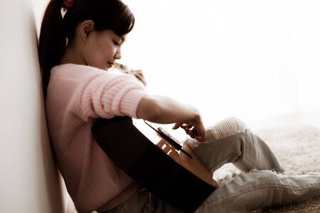 A beautiful asian woman playing acoustic guitar