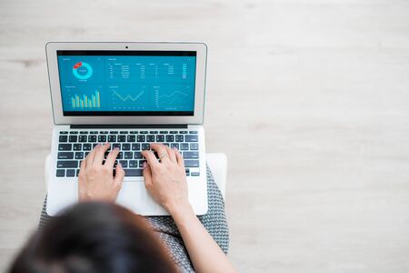 Asian business woman reviewing data in financial charts and graphs. Accounting