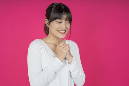 asian woman keeps hands on chest near heart, shows her kindness or favour, expresses sincere emotions, being kind hearted and honest. Body language and real feelings conceptの写真素材