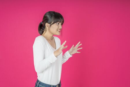 Young asian woman shouting. Shout. Crying emotional  woman screaming on pink studio background. Female half-length portrait.の写真素材
