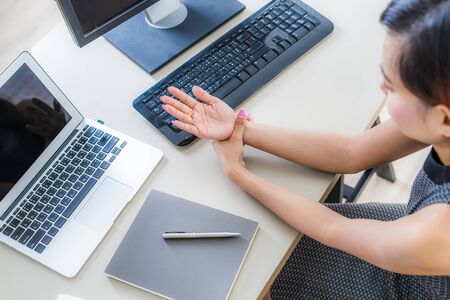 Asian woman holding her wrist pain from using computer. Office syndromeの写真素材